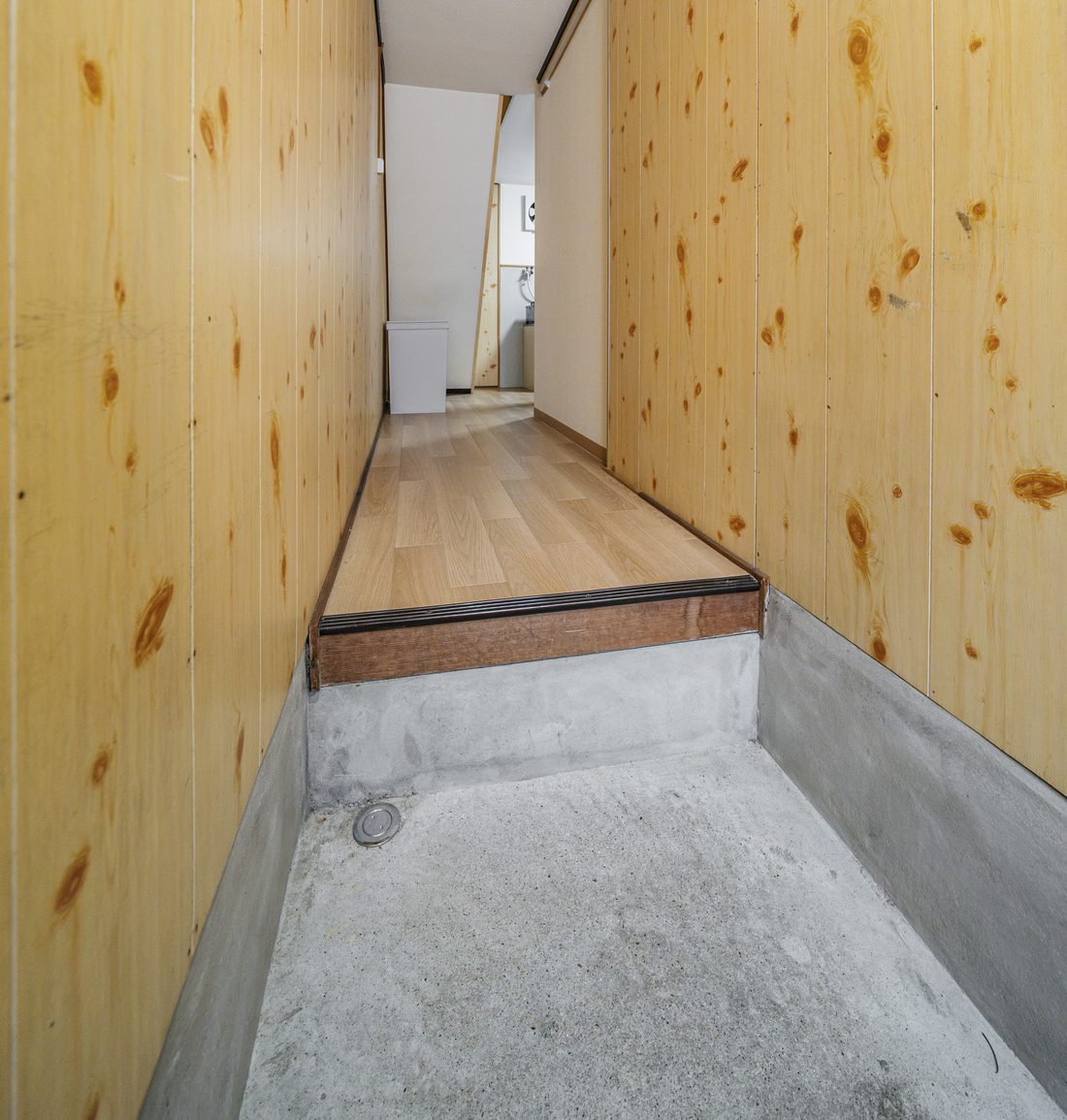 The entrance hall, with a raised wooden floor beyond the concrete